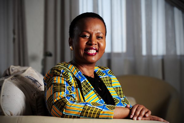 Dr Thembisile Xulu wearing a colourful African print blazer poses for a picture in her lounge.