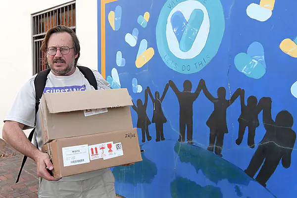 Dr Hermann Reuter stands outside the central clinic in George holding a box of medications.
