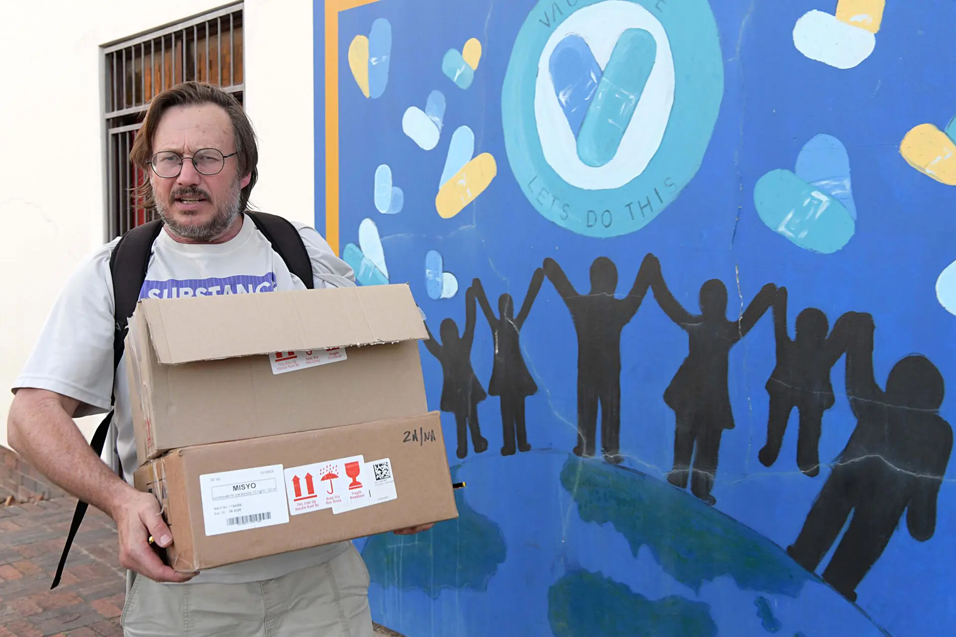 Dr Hermann Reuter stands outside the central clinic in George holding a box of medications.