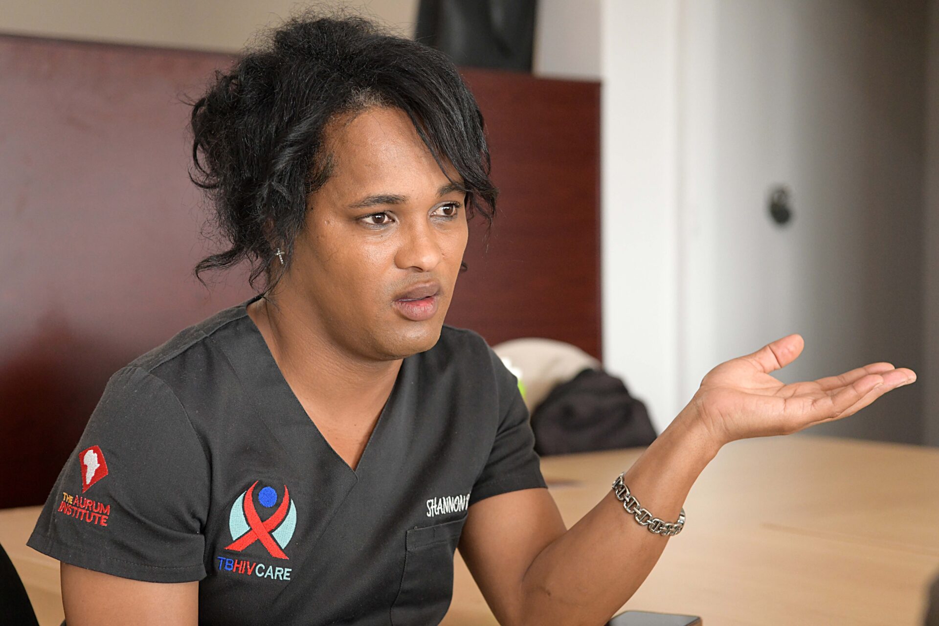 TB HIV Care peer educator Shannon Damons, wearing a black uniform, gestures as she speaks during an interview with Spotlight.