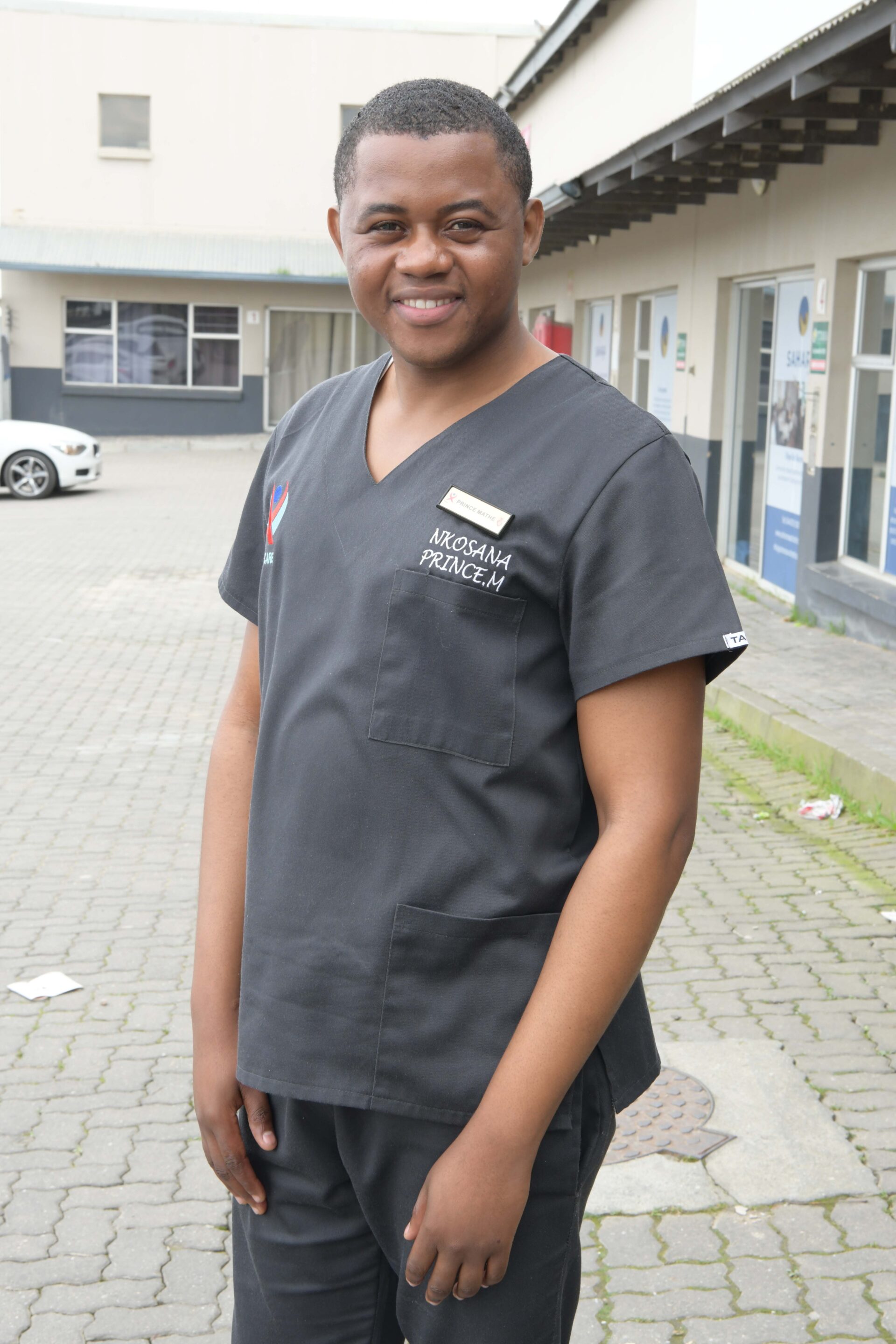 Prince Mathe, TB HIV Care’s District Project Coordinator, poses for a photograph outside the George office, dressed in his black uniform.