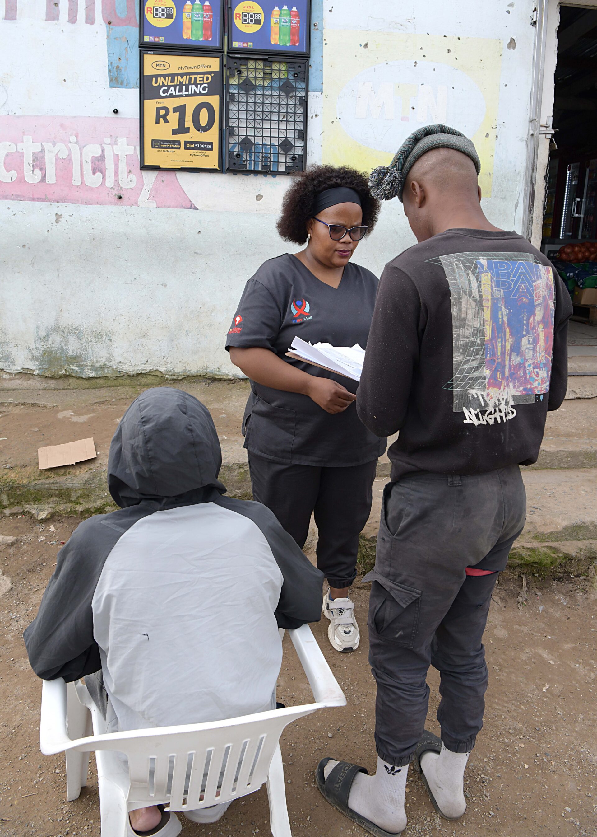 Counsellor Ncumisa Nkonjane engages with two men outside a spaza shop during an outreach by TB HIV Care.