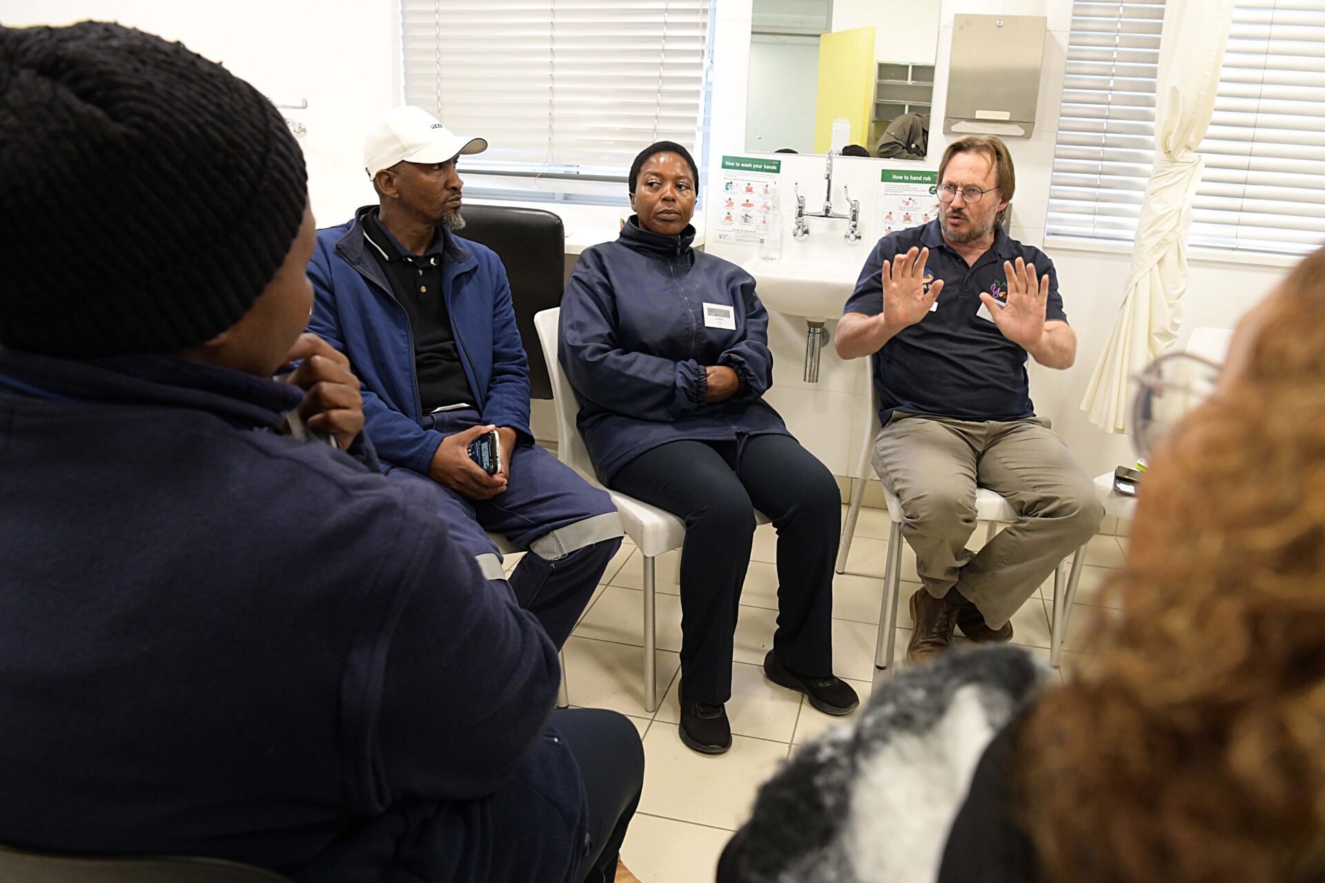 Dr Hermann Reuter sits in a circle with clients and healthcare workers during a group discussion.