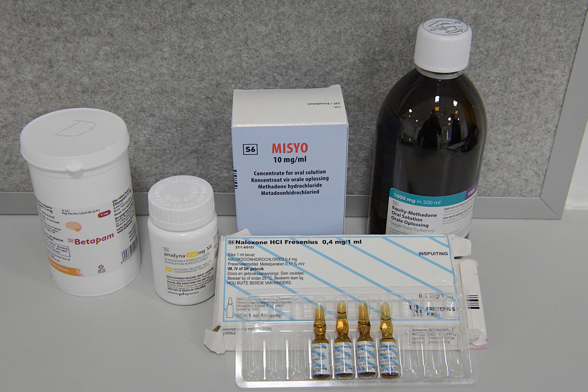 Assorted pills, medication vials, and liquid medicine used in the treatment of alcohol and nicotine use disorders.
