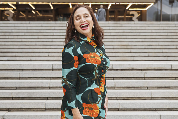 A smiling Marlene le Roux standing in front of the stairs of the Artscape Theatre Center in Cape Town.