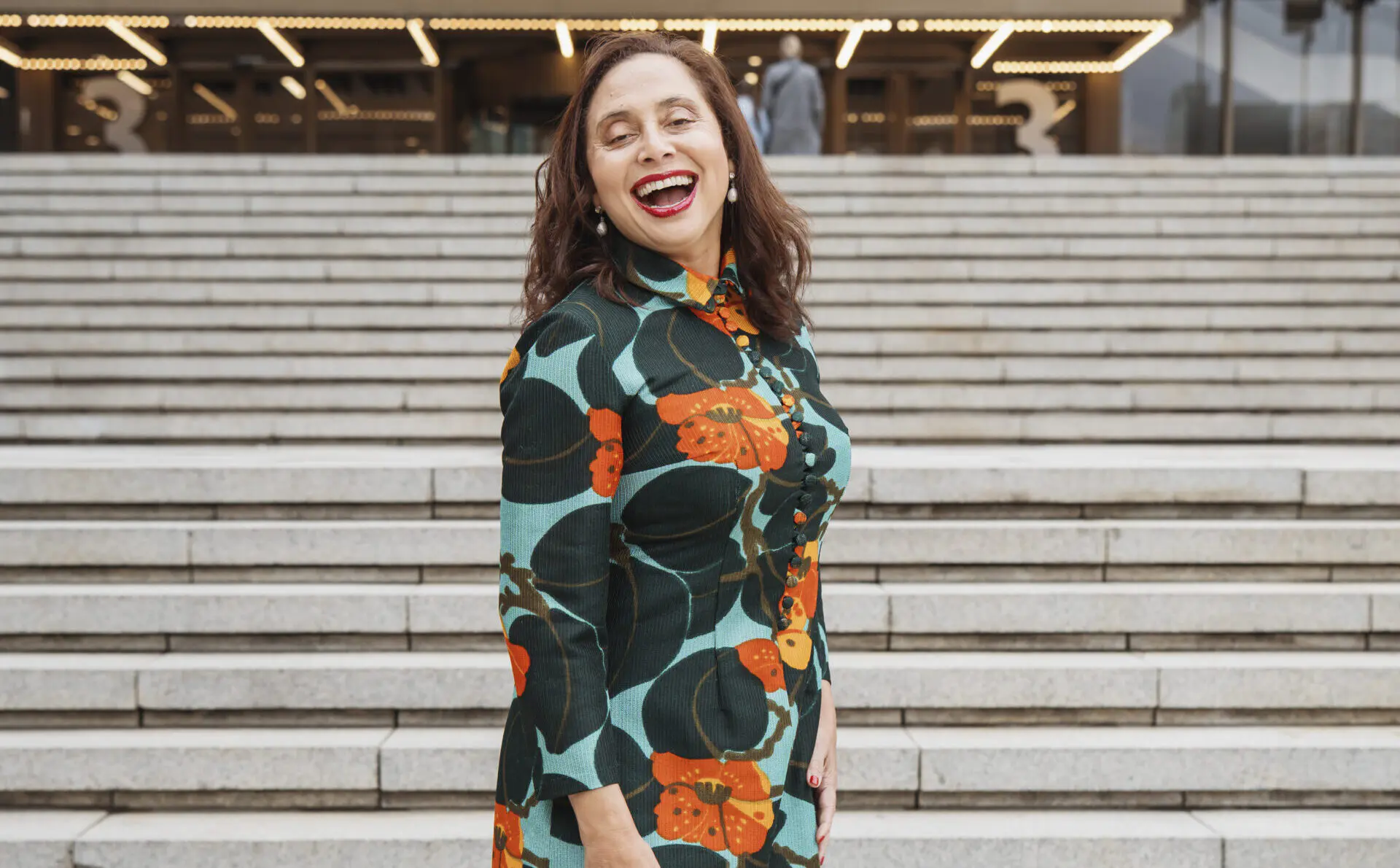 A smiling Marlene le Roux standing in front of the stairs of the Artscape Theatre Center in Cape Town.