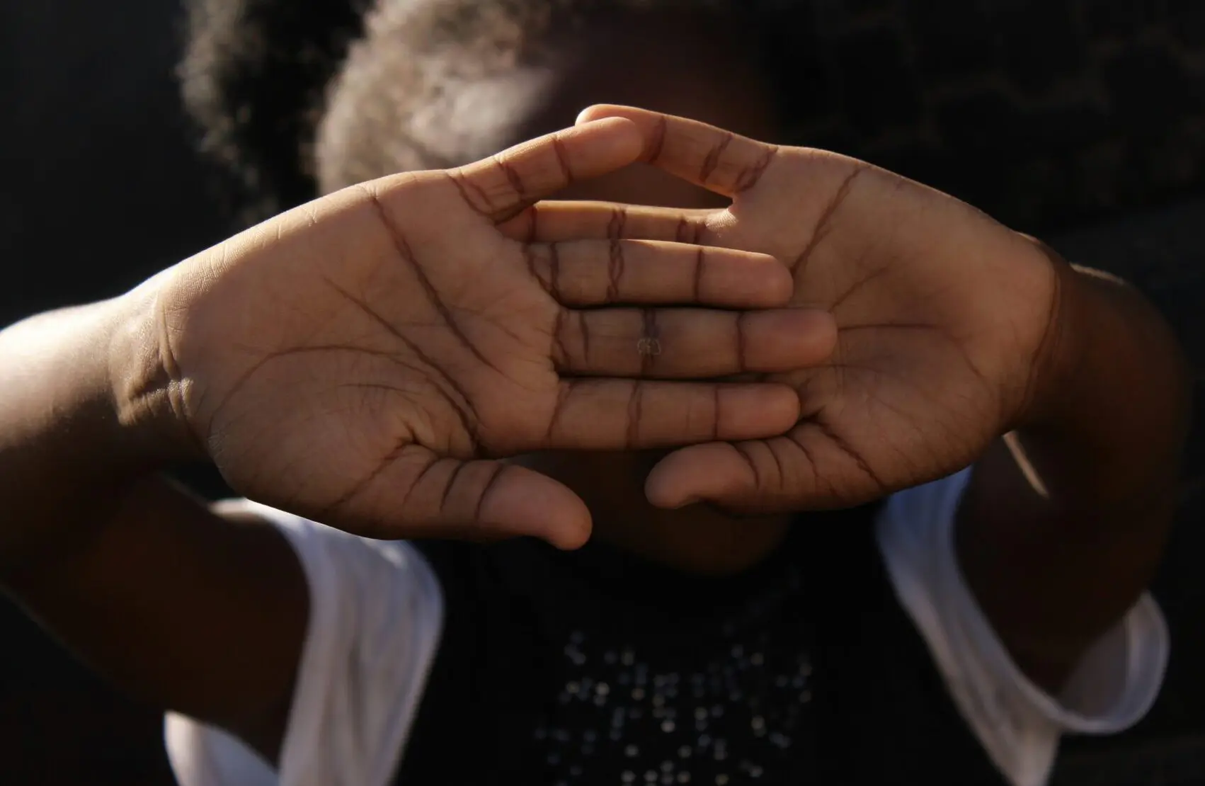 A child covering her face with her hands.